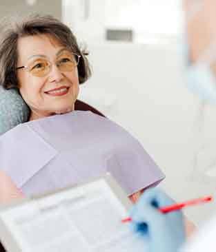 Dentist taking notes during senior patient’s consultation