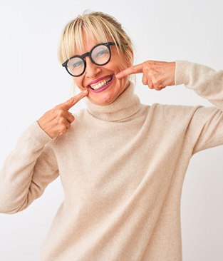 Happy, middle-aged woman pointing at her teeth