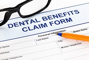 Pen and glasses lying on top of dental benefits claim form