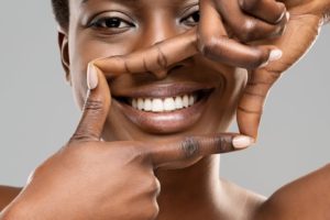 woman framing her white teeth with her hands