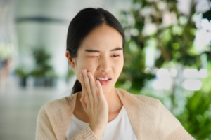 Woman rubbing her jaw because of sensitive dental implant