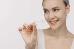 Woman holding Invisalign aligner between two fingers